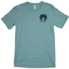 Spikeodelic volleyball men's t-shirt in dusty blue. Front pocket graphic is man's face with afro made from volleyballs and players spiking volleyballs. Man's glasses are round and feature volleyballs. The words "Spikeodelic" are below the graphic. The maj