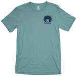 Spikeodelic volleyball men's t-shirt in dusty blue. Front pocket graphic is man's face with afro made from volleyballs and players spiking volleyballs. Man's glasses are round and feature volleyballs. The words "Spikeodelic" are below the graphic. The maj