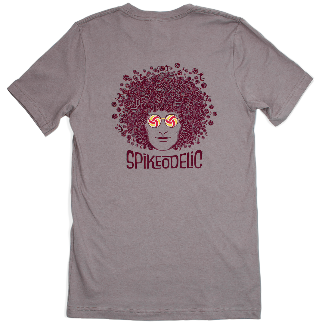 Spikeodelic volleyball men's t-shirt in pebble. Back graphic is man's face with afro made from volleyballs and players spiking volleyballs. Man's glasses are round and feature volleyballs. The words "Spikeodelic" are below the graphic. The majority of the